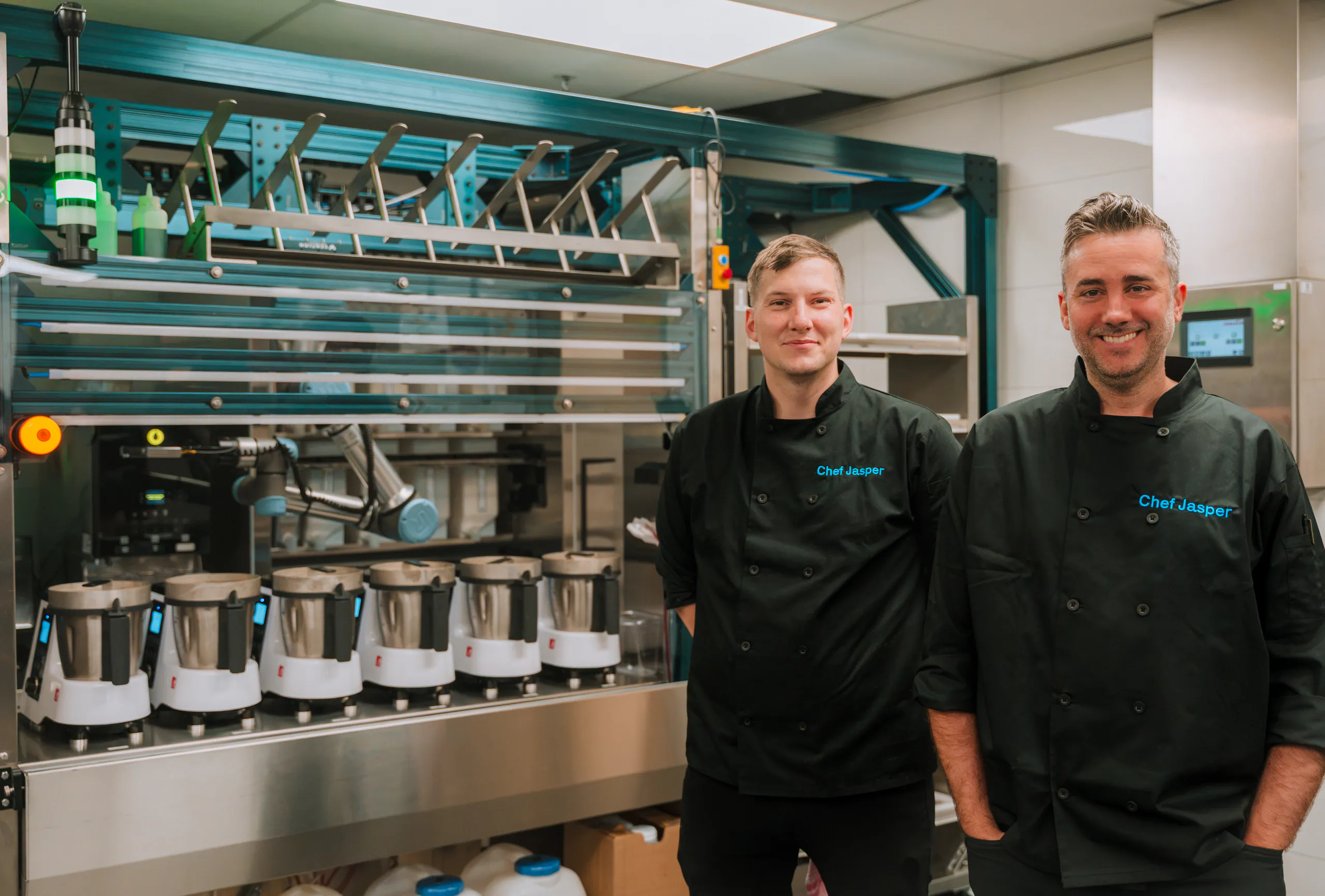 Deux chefs de Chef Jasper debout près de la ligne de cuisson robotisée