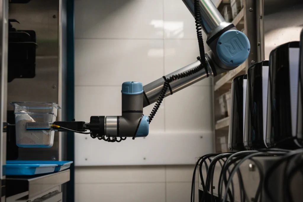 Le bras robotisé de Chef Jasper qui saisit un contenant d’ingrédients