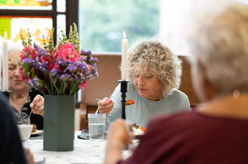 Residents sharing a meal in a full dining room
