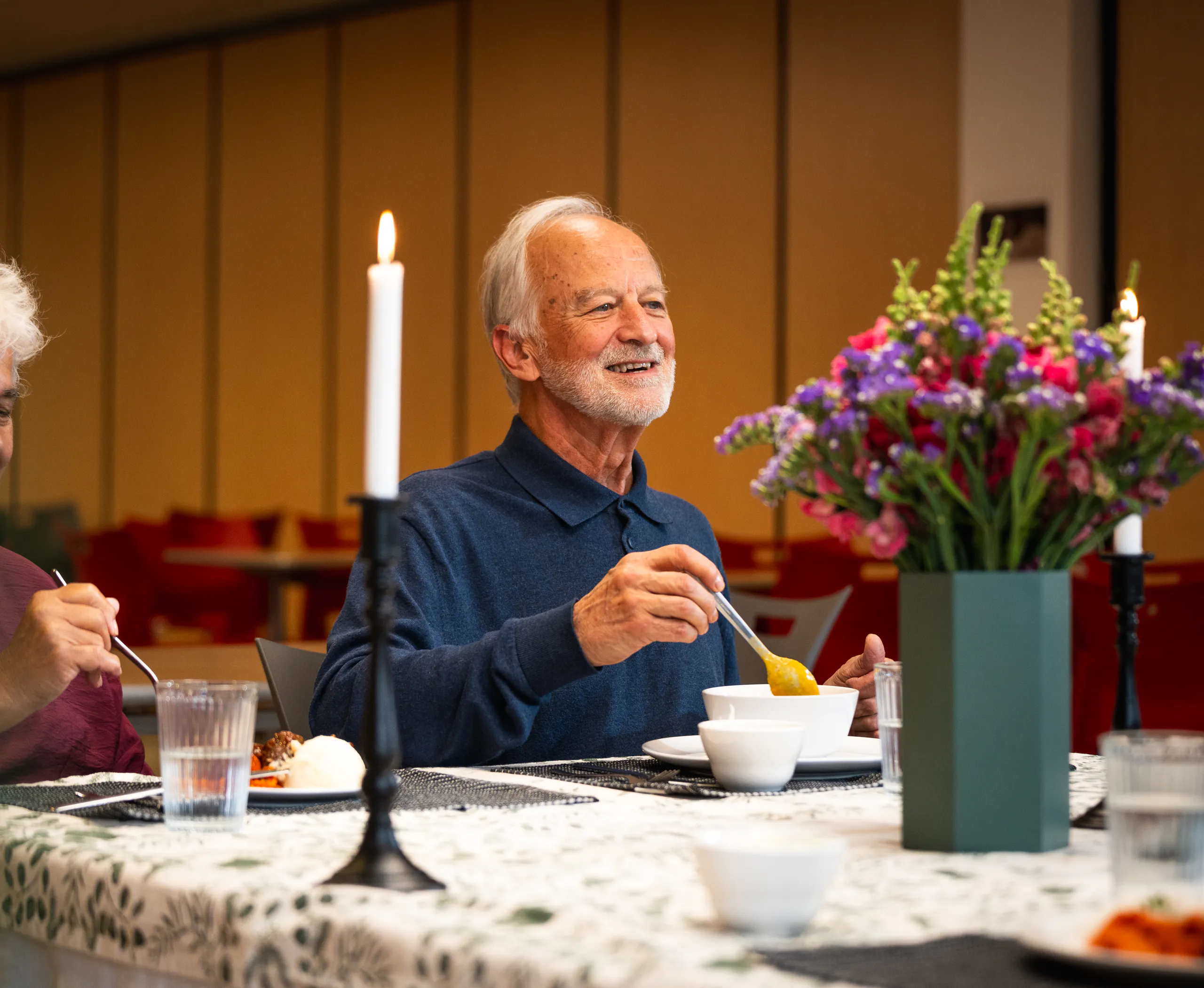 An independent living resident enjoying dinner at a table with flowers