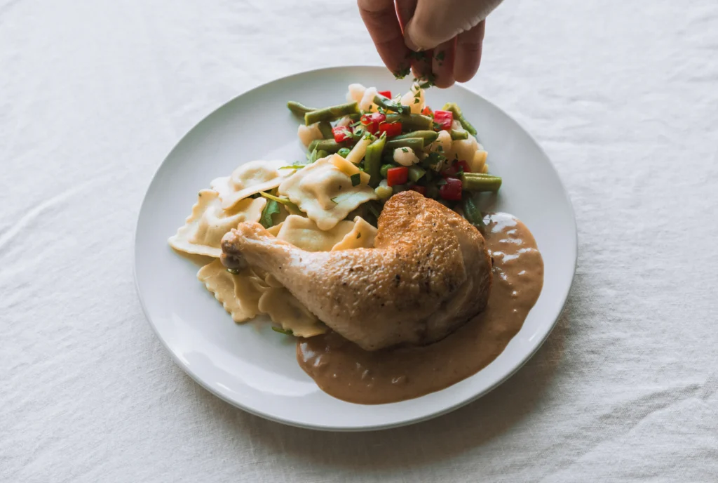 Roast chicken leg with ravioli and vegetables