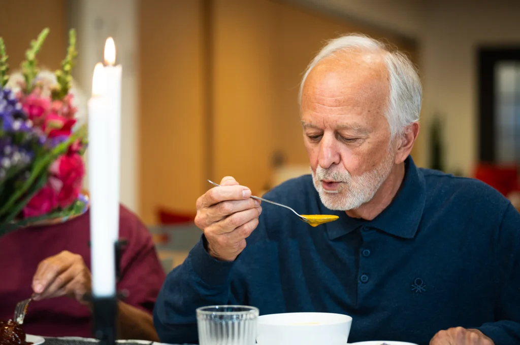 Resident enjoying a spoonful of soup at the dining table