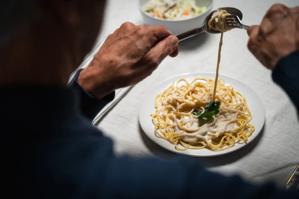 Un résident qui enroule des spaghettis Alfredo