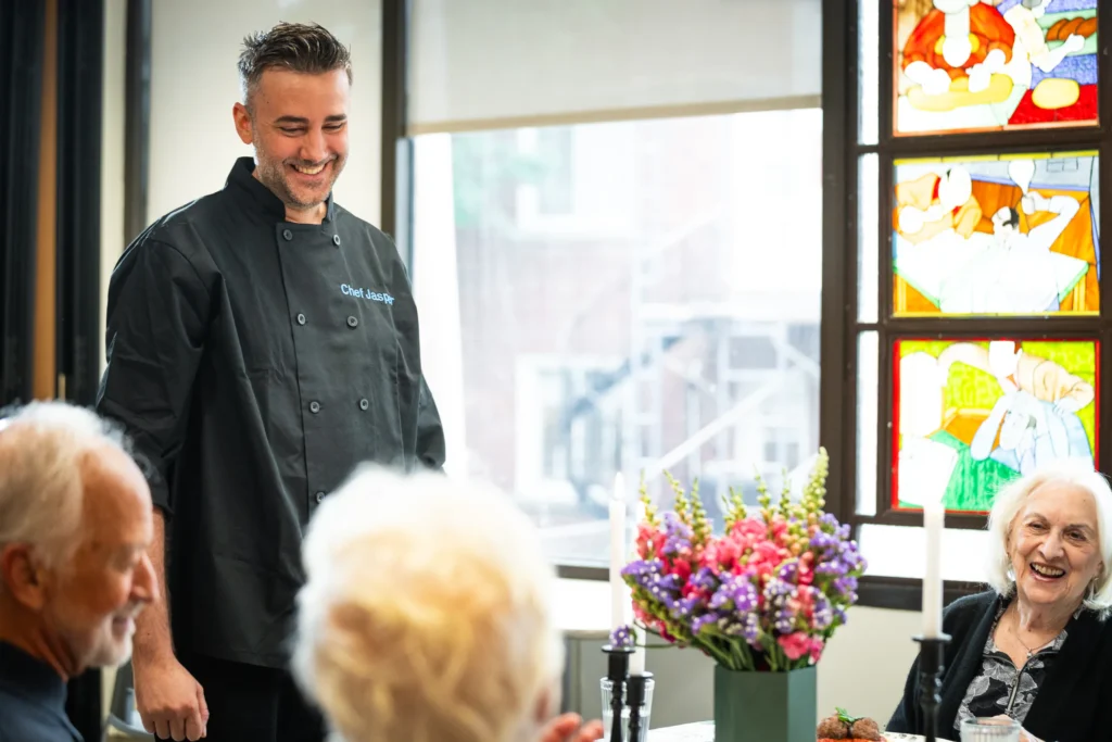 Un chef de Chef Jasper qui rit avec des résidents à table