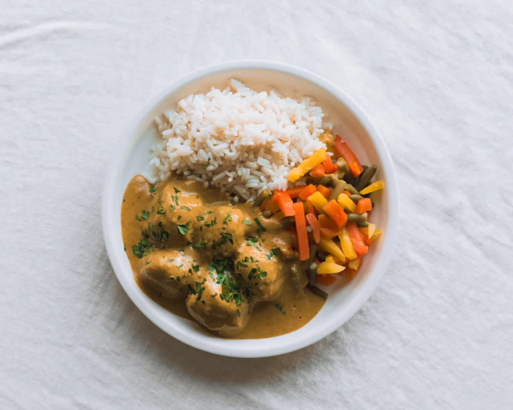 Boulettes de poulet au beurre avec riz et légumes variés